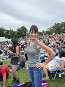 a woman in a tank top stands in front of a crowd of people