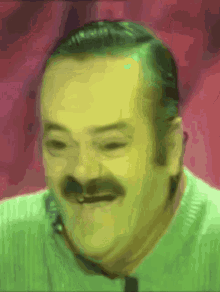 a man with a mustache wearing a green shirt is smiling