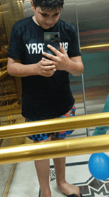 a boy taking a picture of himself in a mirror wearing a shirt that says yяая