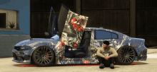 a man sits in front of a car with a spider-man design on it