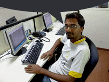 a man sitting at a desk with a computer and a keyboard