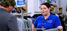 a woman wearing a blue shirt with the word clouds on it is talking to a man in a store .