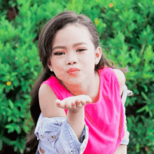 a young girl blows a kiss with her hand