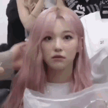 a girl with pink hair is getting her hair done by a man .