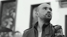 a bald man with a beard wearing a black leather jacket