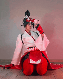 a woman in a red and white kimono takes a selfie with her phone