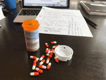 a bottle of orange and white pills sits on a table