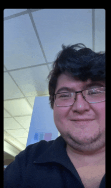 a man with glasses and a black shirt smiles for the camera