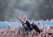 a man in a wheelchair is being lifted in the air by a crowd of people