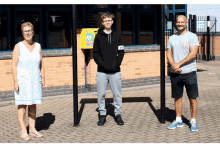 three people standing in front of a yellow box that says ' aed ' on it