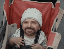 a man with a beard wearing a white hat is sitting in a stroller