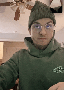 a man wearing glasses and a green hoodie that says great outdoors on it