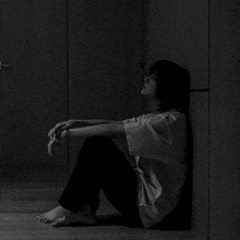 a black and white photo of a woman sitting on the floor