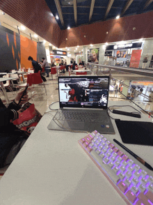 a person sitting at a table with a laptop and a keyboard in front of a sign that says atomic