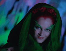 a woman with red hair and green leaves on her face smiles