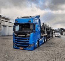 a blue truck is parked on a brick pavement in a parking lot .