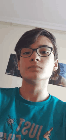 a young man wearing glasses and a blue shirt that says taul