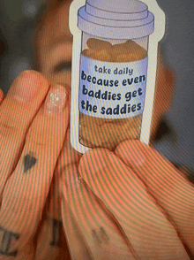 a person is holding a sticker that says take daily because even baddies get the saddles