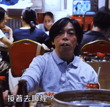 a man sitting at a table with a can of soda in front of him with chinese writing on it