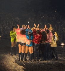 a group of people standing in a circle with their hands up