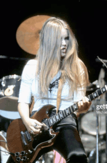 a woman with long hair is playing a guitar in front of a drum set