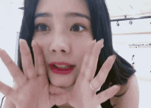 a woman with long black hair is making a face with her hands .