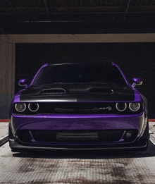 a purple dodge challenger srt hellcat is parked in a garage