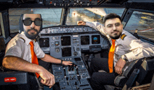 two pilots in an airplane cockpit with a life vest