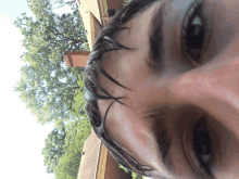 a close up of a person 's face with a brick house in the background