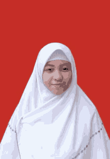 a woman wearing a white hijab is standing in front of a red background and smiling .