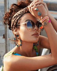 a woman wearing a leopard print headband and sunglasses holds her hand to her face