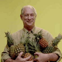 a man holding pineapples in his hands and smiling