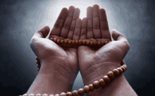 a person is praying with a wooden rosary in their hand