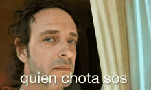 a man looking out a window with the words quien chota sos written on the bottom