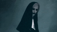 a nun with a scary face is standing in the dark in a dark room .