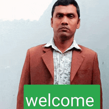 a man in a suit holds a green welcome sign