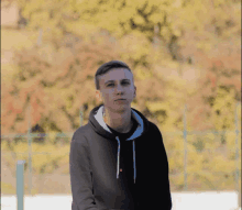 a young man wearing a black hoodie with white strings and a red button on the front