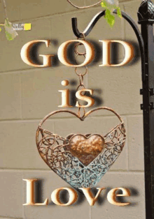 a sign that says `` god is love '' with a heart shaped pendant hanging from a pole .