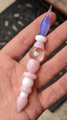 a hand is holding a purple and pink glass item