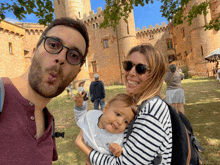 a man making a funny face while holding a baby in front of a castle