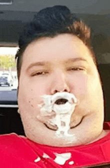 a man in a red shirt with whipped cream on his face .