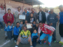 a group of people posing for a picture with one man wearing a yellow peugeot jersey