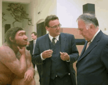 a man in a suit is talking to two other men in suits