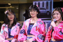 three girls wearing pink jackets with 48 on them