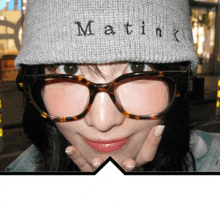 a woman wearing glasses and a beanie that says matink on it