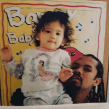 a little girl is sitting on a man 's lap in front of a book called baby baby