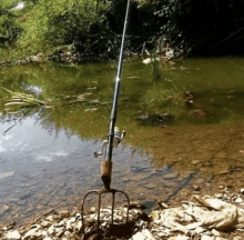 a fishing rod with a fork attached to it sits in the water