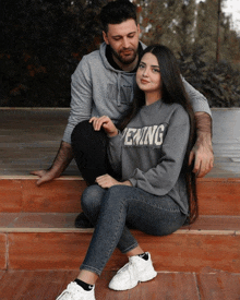 a man and a woman are posing for a picture and the woman is wearing a sweatshirt that says " mewing "