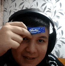 a man wearing headphones holds up a milky way bar