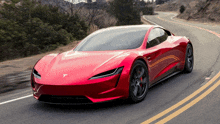 a red tesla model s is driving down a curvy road